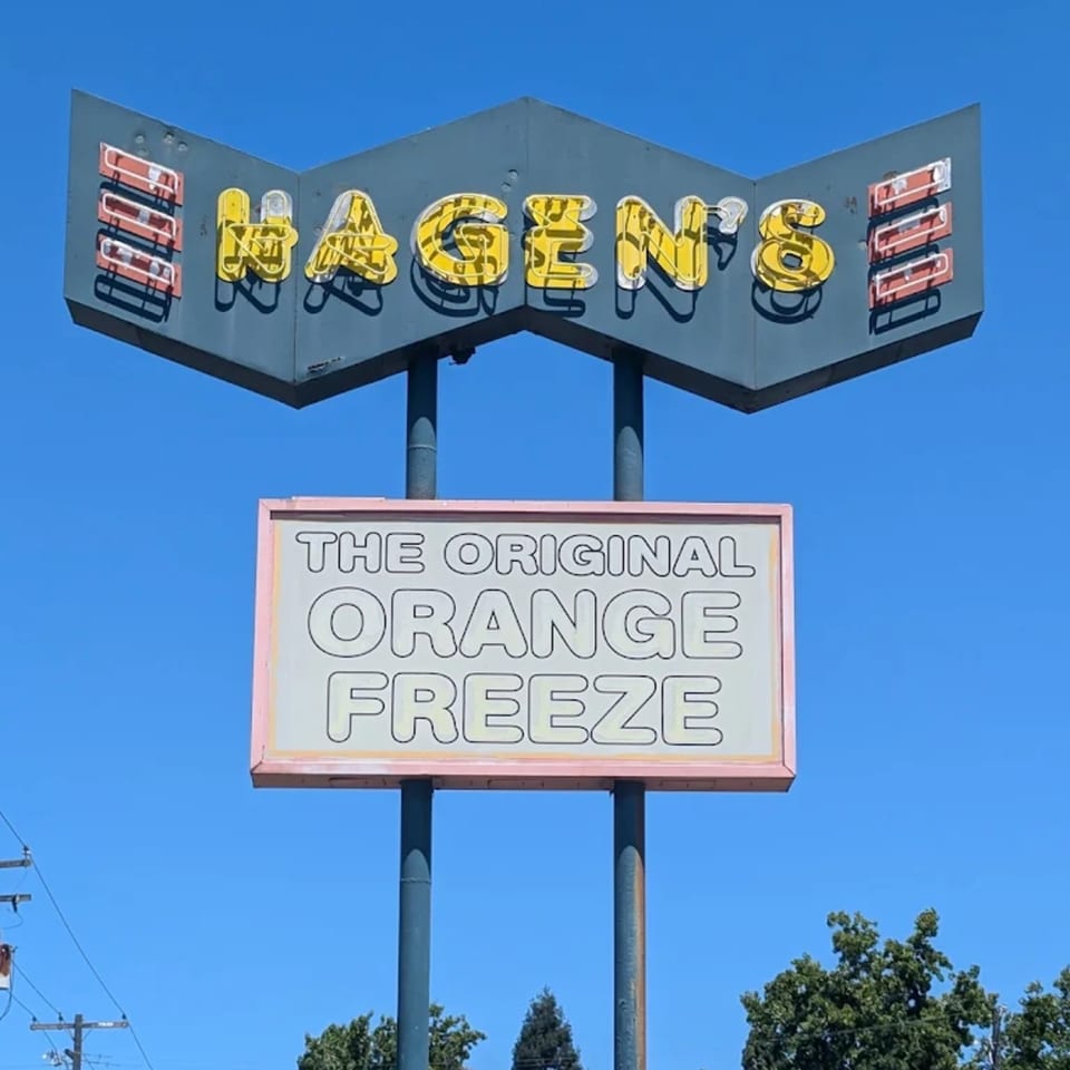 A vintage Hagen's sign with yellow neon letters and a smaller sign advertising "The Original Orange Freeze".